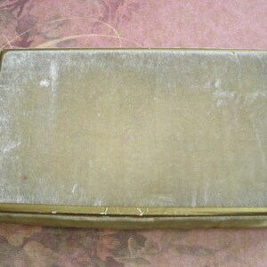 K&ouml;nnte beinhalten: Rechteckige Vintage-Box mit goldfarbenem Metallrahmen und hellgr&uuml;nem Samtdeckel. Die Box hat ein schlichtes, elegantes Design, und der Samt weist Gebrauchsspuren auf.