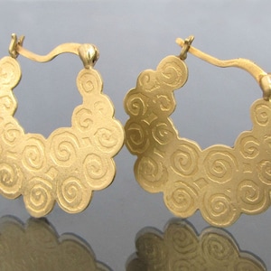 May include: A pair of gold hoop earrings with a swirling, textured design. The earrings are made of a smooth, shiny metal and have a circular shape.
