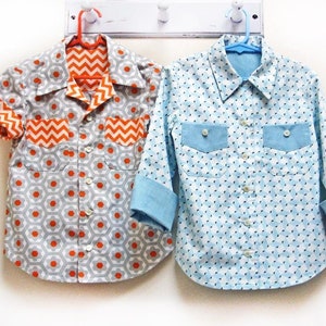 Può includere: Due camicie abbottonate, una con un motivo geometrico in tonalità di grigio e arancione, e l'altra con un motivo geometrico blu e bianco.