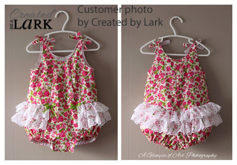 May include: A white floral print baby onesie with a white lace ruffle trim. The onesie is hanging on a white hanger.