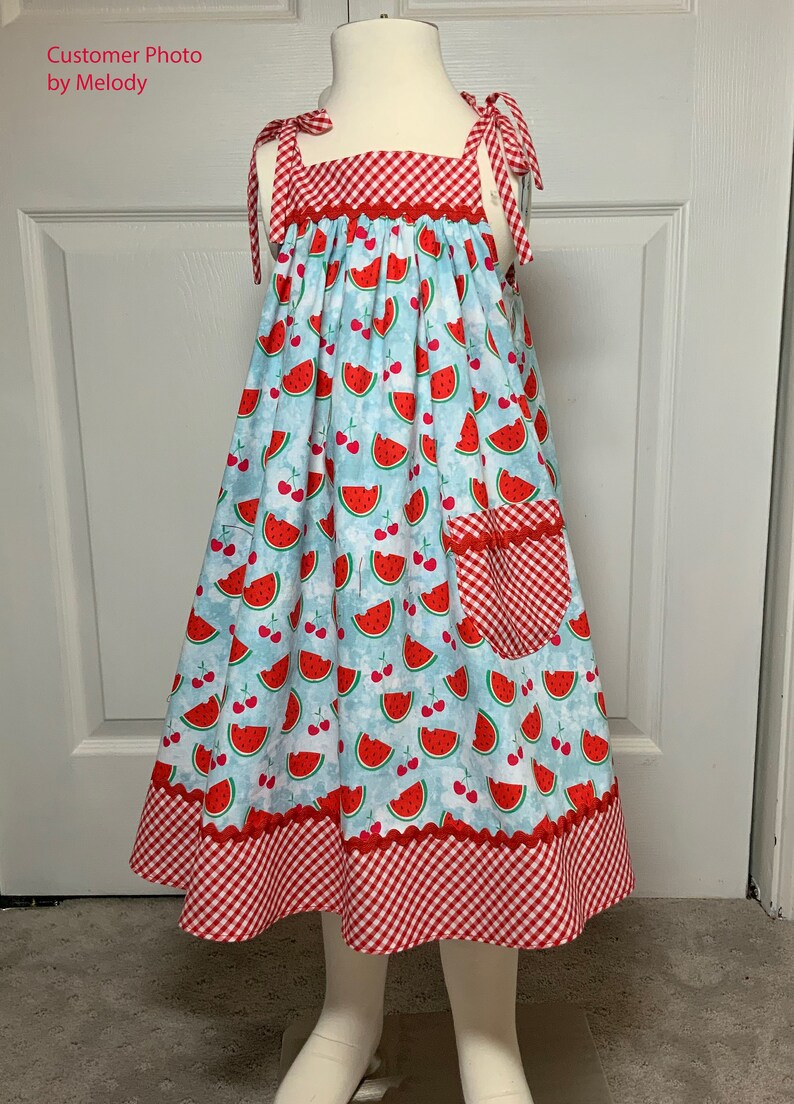 May include: A sleeveless dress with a red and white gingham bodice and a blue and white watermelon print skirt. The dress has a red gingham pocket on the right side and a red gingham trim around the bottom.