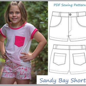 Op de afbeelding: Een PDF-naai-patroon voor Sandy Bay Shorts. Het patroon bevat een lijntekening van de shorts met twee zakken aan de voorkant en twee zakken aan de achterkant. De shorts hebben een tailleband met een knoop en een rits.