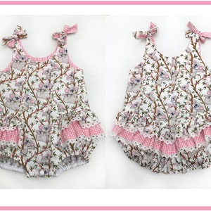 May include: Two white and pink baby onesies with a koala print and pink and white gingham trim. The onesies have a ruffle at the bottom and bows on the straps.