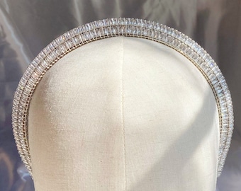 May include: A silver headband with a double row of clear rhinestones. The headband is on a white mannequin head.