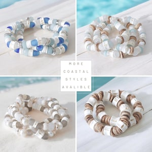 May include: Four images of coastal-themed bracelets. The bracelets feature various combinations of white, blue, and neutral-toned beads. The text "MORE COASTAL STYLES AVAILABLE" is displayed in a white box.