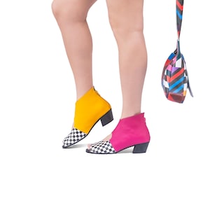 May include: A pair of women's shoes with contrasting colors. One shoe is yellow with black and white checkered toe, the other is pink with black and white checkered toe.