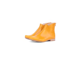 May include: A pair of yellow leather ankle boots with a pointed toe and a low heel.