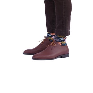 Peut inclure: Une paire de chaussures en cuir marron &agrave; lacets avec un style d&eacute;contract&eacute;. Les chaussures sont port&eacute;es avec des chaussettes &agrave; motifs color&eacute;s.