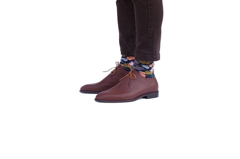 Peut inclure: Une paire de chaussures en cuir marron &agrave; lacets avec un style d&eacute;contract&eacute;. Les chaussures sont port&eacute;es avec des chaussettes &agrave; motifs color&eacute;s.