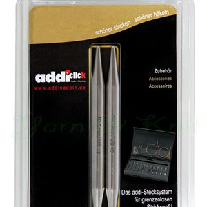 May include: A package containing AddiClick knitting needles. The needles are silver-colored and labeled with size 10.0 mm/US 15. The packaging includes text in German and English, advertising the "addi-Stecksystem" for knitting.