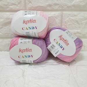 Puede incluir: Tres ovillos de hilo Katia Candy en rosa, morado y blanco con un patrón de color degradado. El hilo está etiquetado con el nombre de la marca Katia y el nombre del hilo Candy. El hilo es 100% algodón y lavable a máquina.