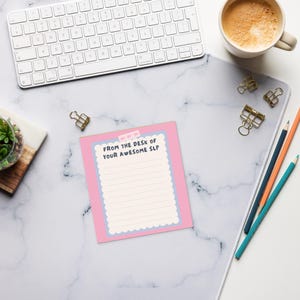 May include: A pink notepad with the text "FROM THE DESK OF YOUR AWESOME SLP" sits on a marble-patterned desk mat. A white keyboard, pencils, and a cup of coffee are also on the desk.