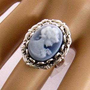 May include: A silver ring with a blue cameo featuring a woman's profile. The cameo is set in a detailed silver frame.