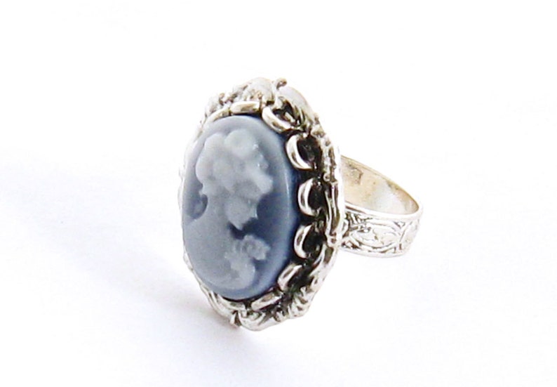May include: A silver ring with a blue cameo featuring a woman's profile.