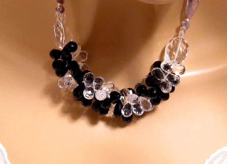 K&ouml;nnte beinhalten: Eine schwarze und klare Kristallperlenkette. Die Kette besteht aus facettierten Perlen und ist auf einer silbernen Kette aufgef&auml;delt.