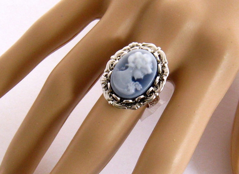May include: A silver ring with a blue cameo featuring a woman's profile. The cameo is set in a detailed silver frame.