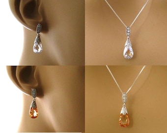 May include: A set of teardrop-shaped earrings and a matching necklace with clear and amber stones. The jewelry is made of silver and features a delicate design.