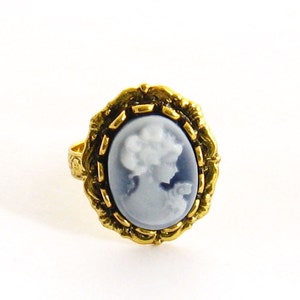 May include: A gold ring with a blue and white cameo featuring a woman's profile.