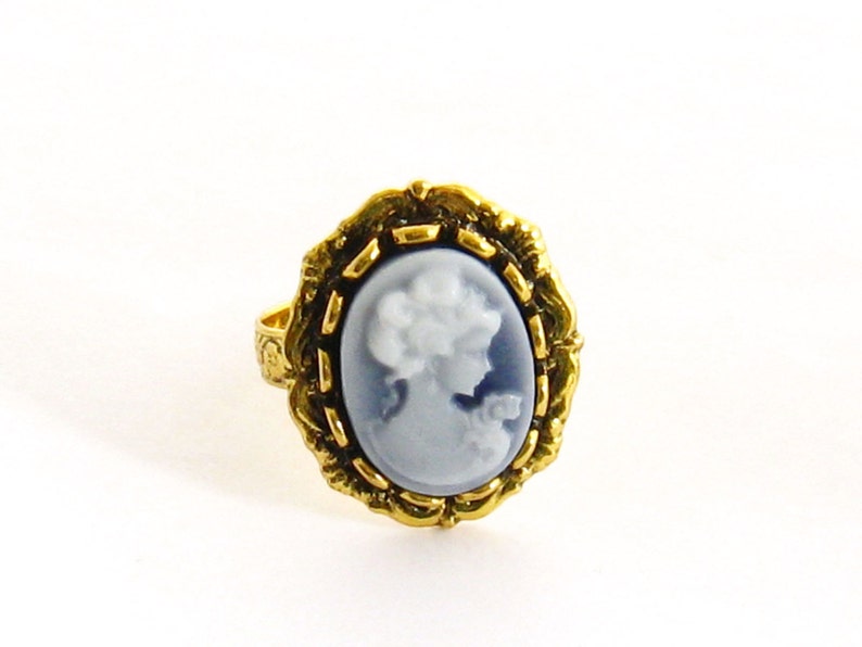 May include: A gold ring with a blue and white cameo featuring a woman's profile.