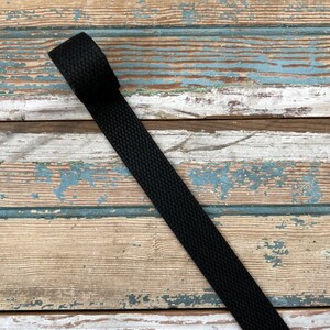 May include: Black woven strap on a wooden surface.