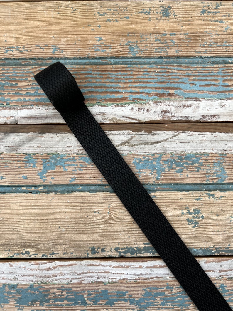 May include: Black woven strap on a wooden surface.