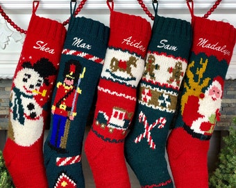 Puede incluir: Cinco calcetines de Navidad de punto rojo y verde con ribetes blancos colgados de una repisa de chimenea. Los calcetines están decorados con varios temas navideños, incluyendo un muñeco de nieve, un soldado de juguete, un caballo de balancín, hombres de jengibre y Santa Claus. Los calcetines están personalizados con los nombres Shea, Max, Aiden, Sam y Madalyn.