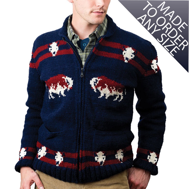 May include: A navy blue knitted cardigan with red and white stripes and a white buffalo design. The cardigan has a zipper closure and two pockets.
