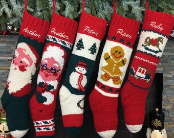 May include: Five red and white knitted Christmas stockings with different embroidered designs, including Santa Claus, a snowman, a gingerbread man, a rocking horse, and a toy train. The stockings are hung on a fireplace mantel and are personalized with the names "Arthur", "Heather", "Peter", "Piper", and "Ruby".