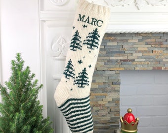 May include: White knitted Christmas stocking with green stripes and a green tree pattern. The stocking is personalized with the name "MARC".