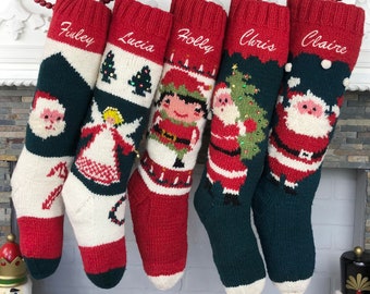 Puede incluir: Cinco calcetines de Navidad personalizados con diferentes escenas navideñas y nombres bordados. Los calcetines son rojos, verdes y blancos con un fondo blanco y presentan a Papá Noel, un ángel, un elfo y un árbol de Navidad.