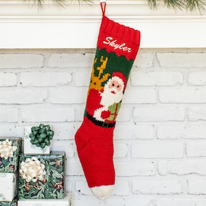 May include: A red knit Christmas stocking featuring a green band at the top with a white embroidered name Skyler. The center displays a knitted graphic of Santa Claus with a white beard and red hat, accented by a yellow reindeer silhouette above.