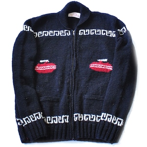 May include: A black zip-up sweater with white and red knit designs of curling stones. The sweater has a white knit band around the neck, cuffs, and hem.