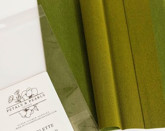 Può includere: Carta crespa doublette nelle tonalità verde felce e muschio. La confezione riporta il testo Petals & Pearls Design, Doublette Crepe Paper, Fern/Moss e le dimensioni di 25 cm x 250 cm. La carta ha una superficie testurizzata e increspata.