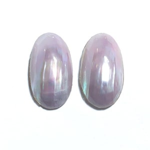 May include: A pair of oval-shaped earrings with a pearlescent finish. The earrings are a light purple color with iridescent highlights.