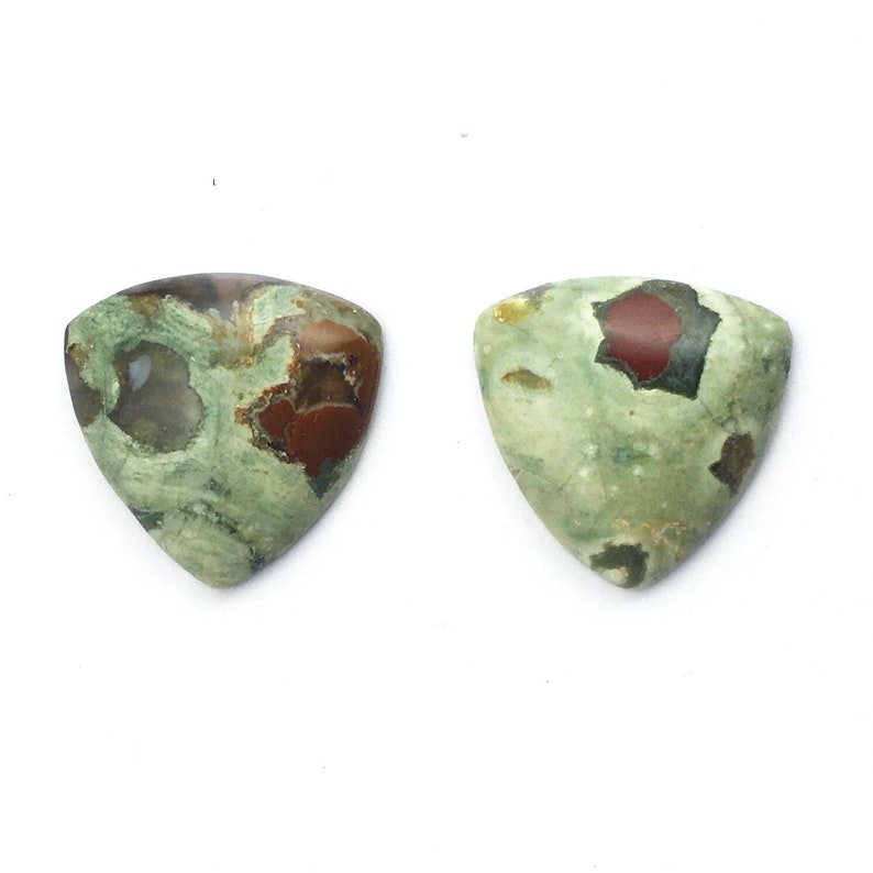 May include: Two triangular green, brown, and red jasper cabochons. The cabochons have a mottled pattern with a variety of colors and shapes.