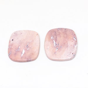 May include: Two square-shaped pink and white agate cabochons with a marbled pattern.