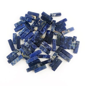 Peut inclure: Un tas de perles de pierres précieuses bleues et blanches de forme rectangulaire. Les perles sont en pierre naturelle et ont une finition polie.