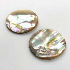 Op de afbeelding: Twee ronde, iriserende parelmoer cabochons. De cabochons zijn lichtbruin van kleur met een parelmoerglans.