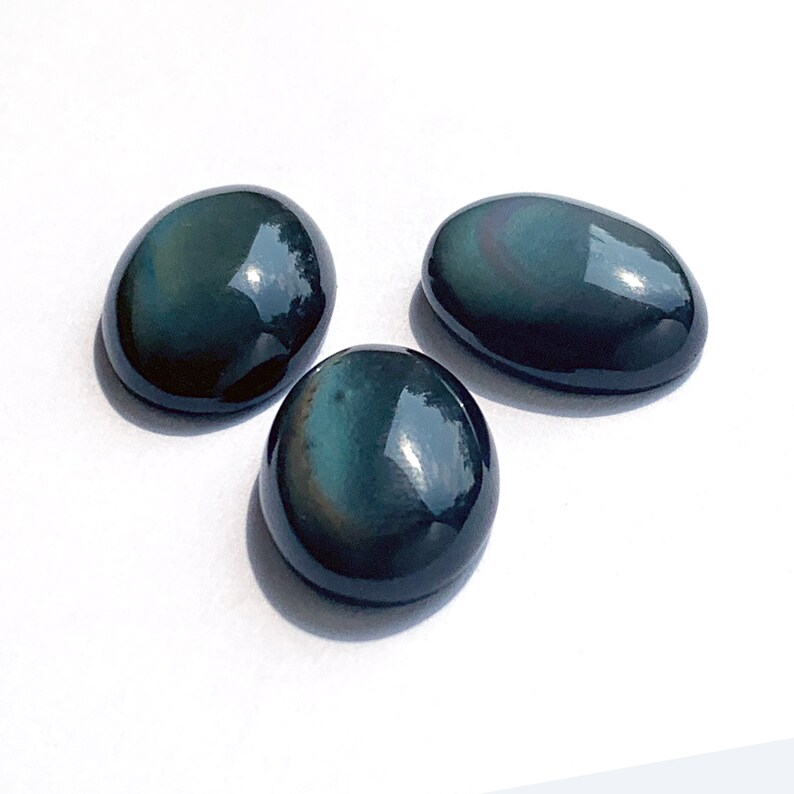 May include: Three oval-shaped obsidian stones with a dark green and black color. The stones are smooth and polished.