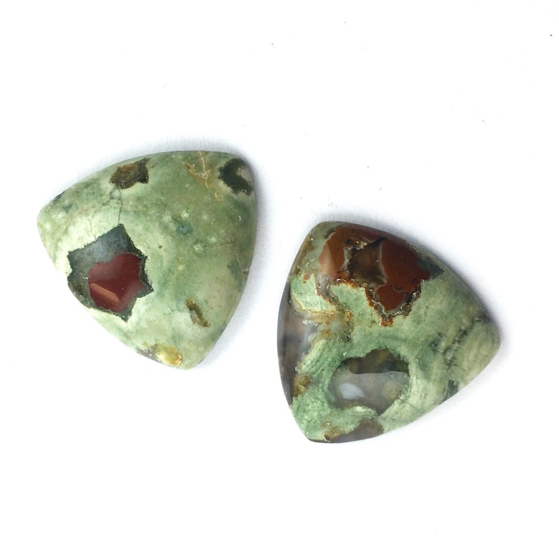 May include: Two triangular green, brown, and red jasper cabochons. The cabochons have a mottled pattern and are polished.