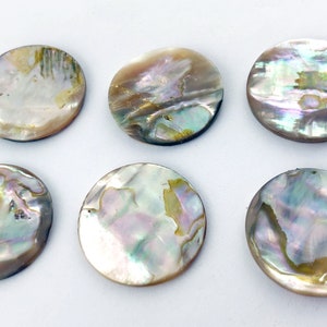 Op de afbeelding: Zes ronde, iriserende parelmoer schijven. De schijven zijn ongeveer 5 cm in diameter en hebben een natuurlijk, organisch patroon.