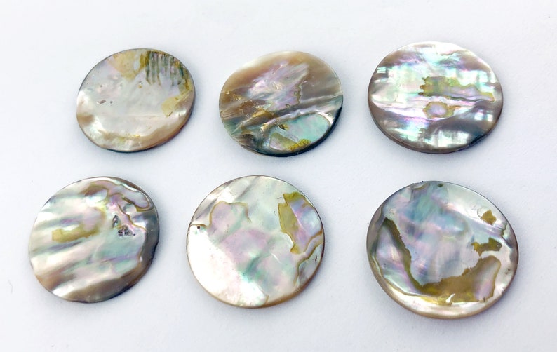 Op de afbeelding: Zes ronde, iriserende parelmoer schijven. De schijven zijn ongeveer 5 cm in diameter en hebben een natuurlijk, organisch patroon.
