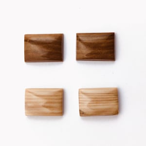 May include: Four rectangular wooden buttons, two are light brown with a wood grain pattern and two are dark brown with a wood grain pattern.