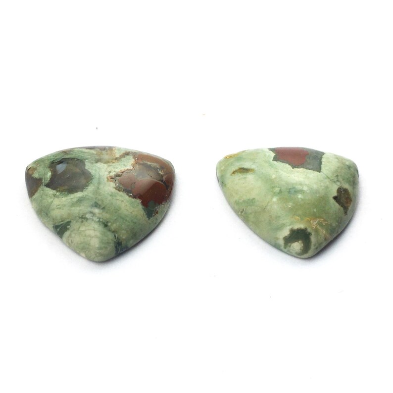 May include: Two triangular green, brown, and red jasper cabochons. The cabochons are polished and have a smooth, glossy finish.