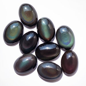 May include: A collection of eight oval-shaped obsidian stones with iridescent rainbow colors. The stones are smooth and polished.