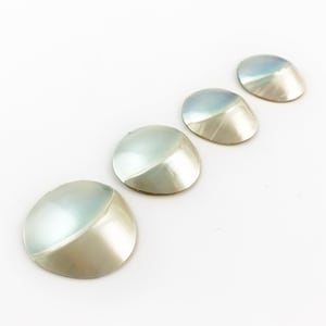 May include: Four iridescent white shell buttons with a rounded, domed shape.