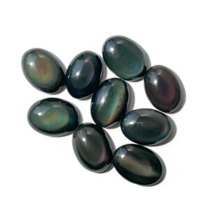 May include: A collection of ten oval-shaped obsidian stones with iridescent rainbow colors. The stones are smooth and polished.