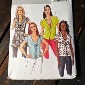 May include: A Butterick sewing pattern, B4986, featuring illustrations of four different women's tops. The pattern includes various styles, such as a collared jacket, a tie-front blouse, and a floral print top. The pattern number is visible.