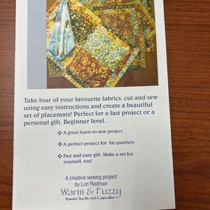 May include: A printed pattern titled "A Bouquet of Placemats" featuring a placemat design with floral patterns. The image includes a placemat with silverware and a napkin. The text says it is a beginner-level sewing project.