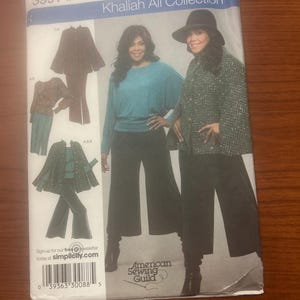 May include: A Simplicity Khaliah Ali Collection sewing pattern envelope, number 3991, size FF 18W-24W. The cover displays illustrations and photographs of a long-sleeved teal top, black wide-leg trousers, and a textured green jacket with a matching hat.